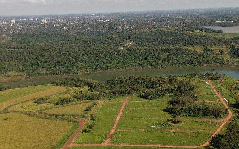 Vista aérea do loteamento na barranca do rio Paraná, com a mancha urbana de Foz do Iguaçu no horizonte.